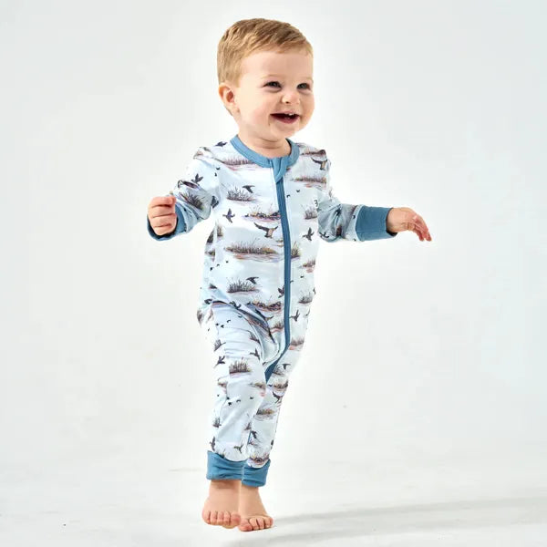 Baby wearing a blue and gray onesie with airplane pattern on a white background