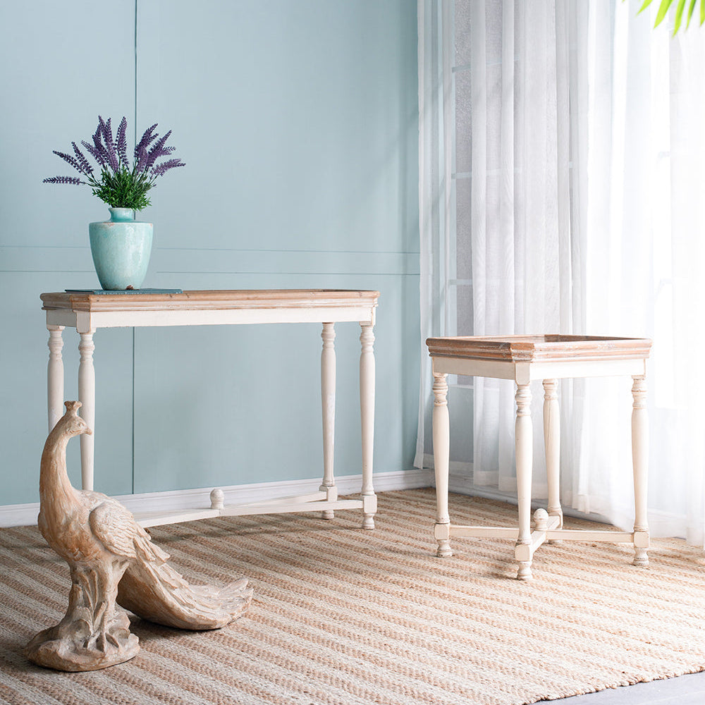 Two wooden tables with a decorative peacock statue and a plant on a light blue wall background.