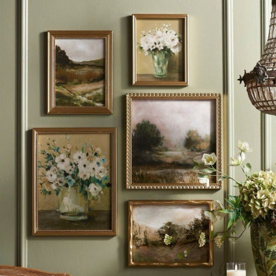 Set of framed paintings on a wall with floral and landscape themes.