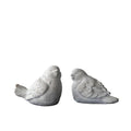 Two gray bird figurines on a book with a black background