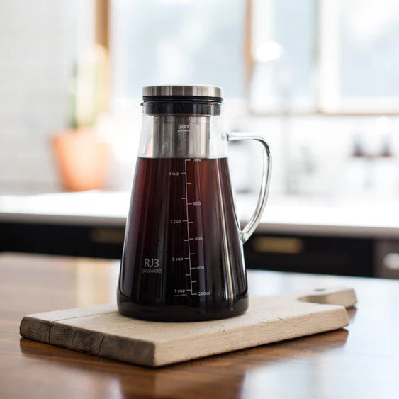 Coffee maker with coffee on a wooden cutting board in a kitchen