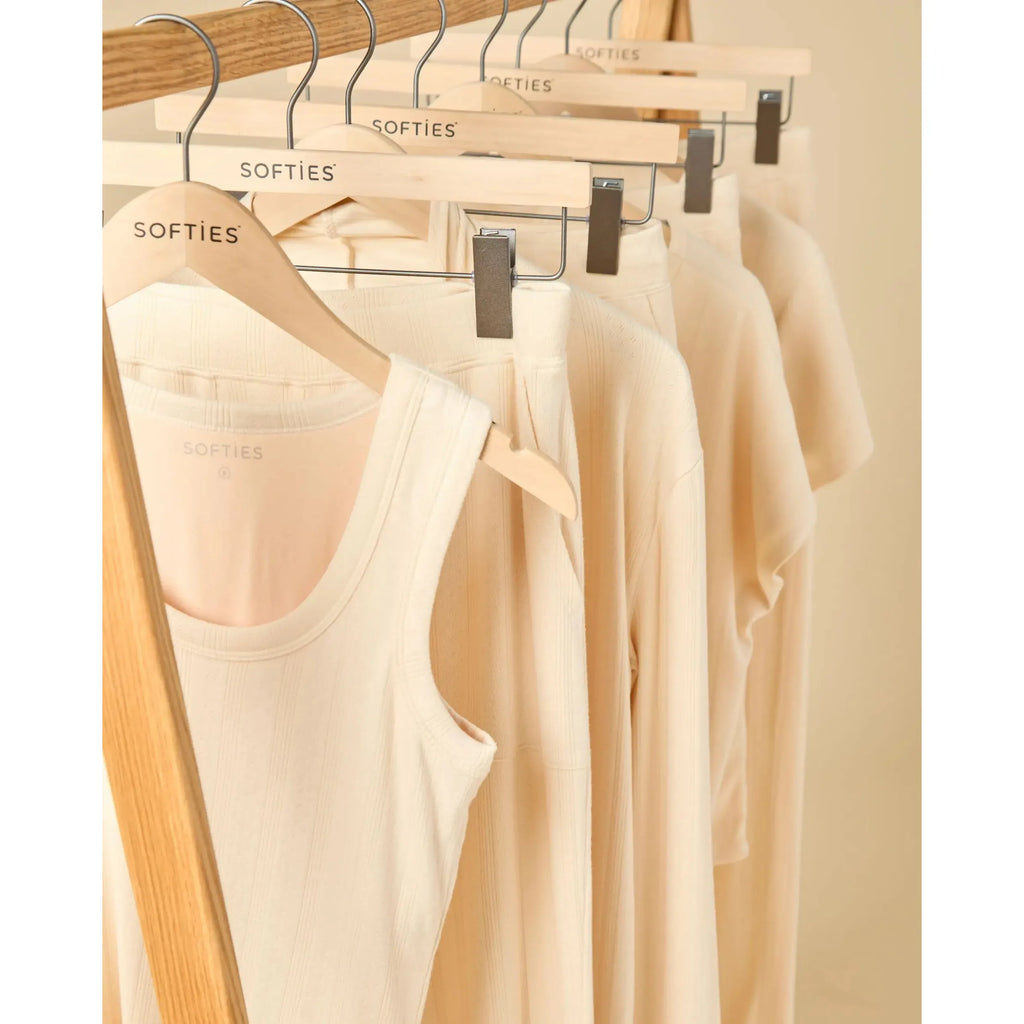 Beige tank tops on hangers with 'SOFTIES' branding.