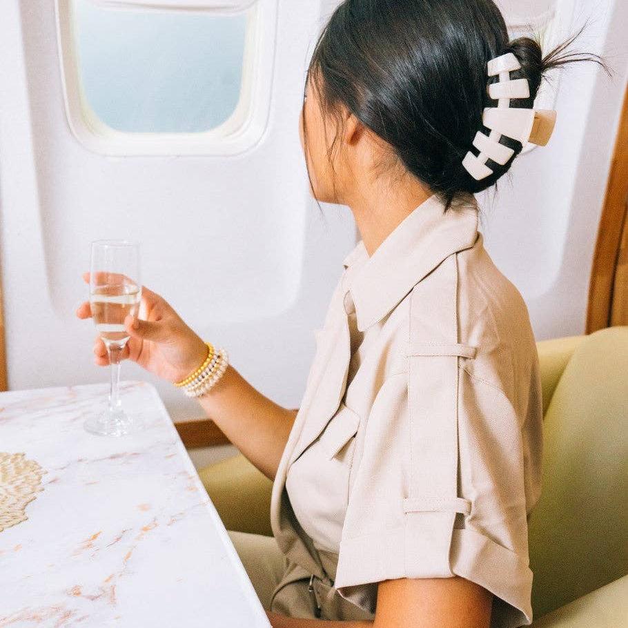Woman sitting on an airplane looking out the window with a almond large hairclaw in her hair.
