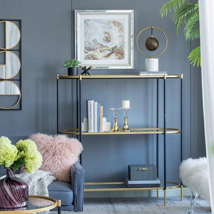 Living room with a gold shelf against a gray wall, featuring decor items and a plant.