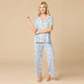 Woman wearing a blue pajama set with a floral pattern on a beige background