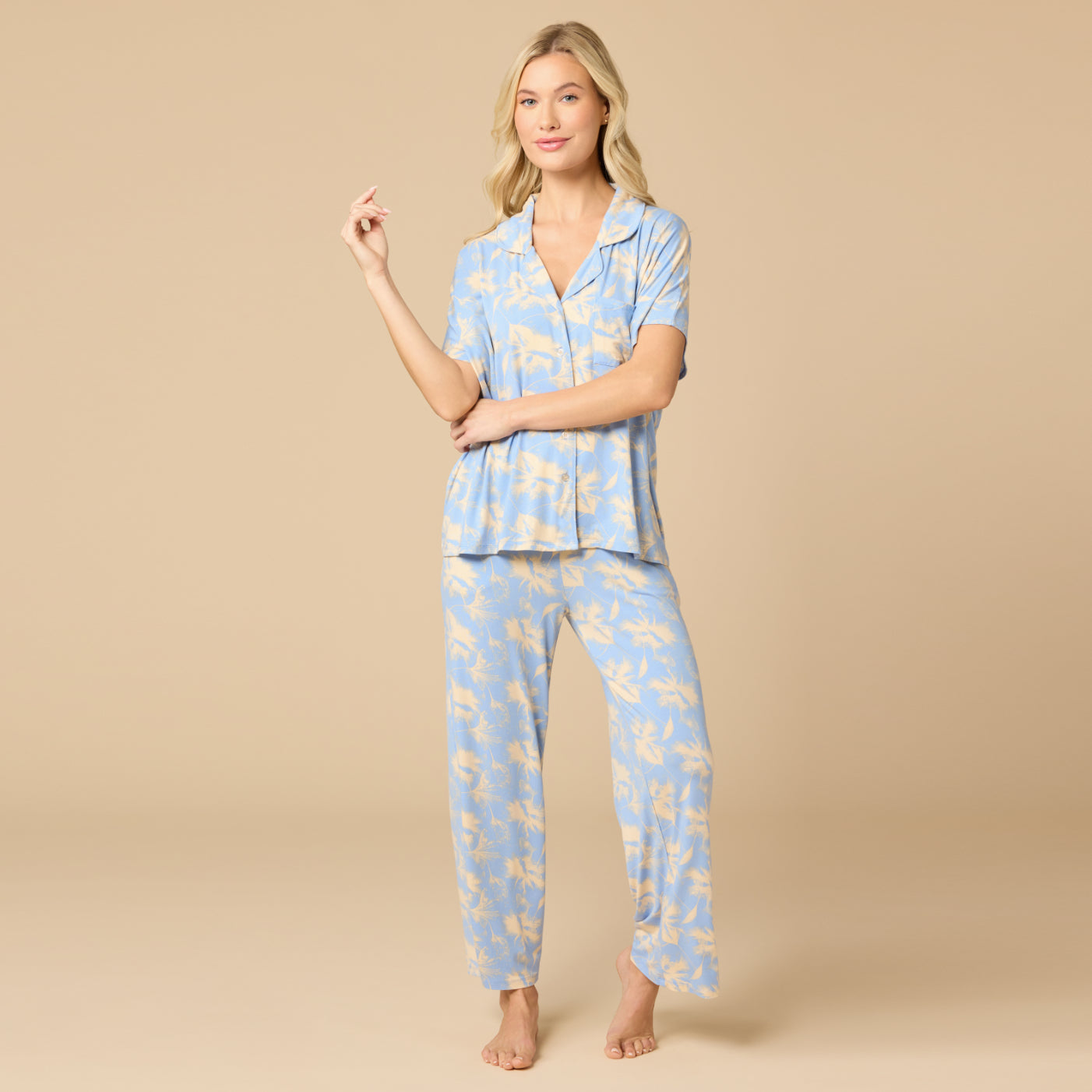 Woman wearing a blue pajama set with a floral pattern on a beige background