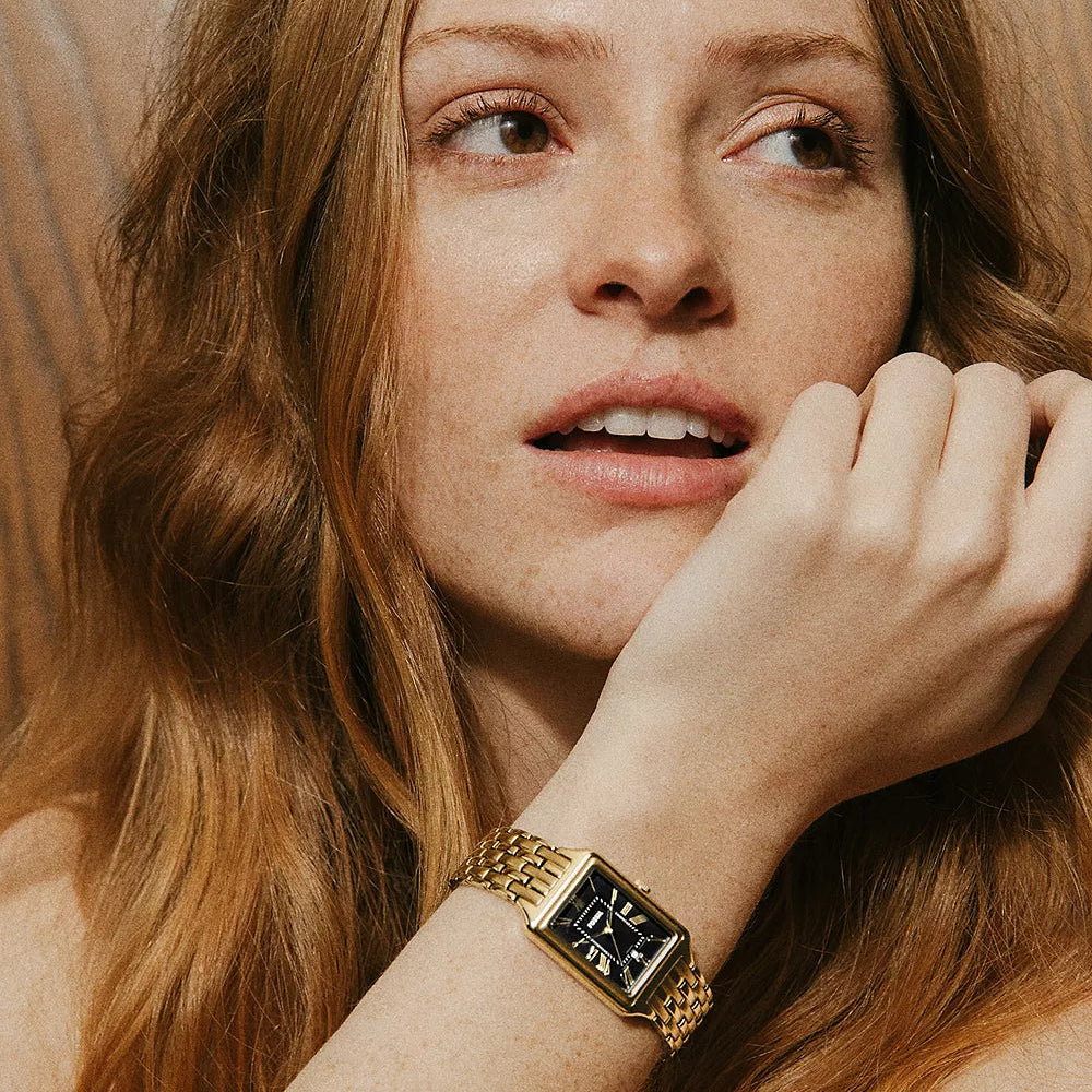 Woman wearing a gold watch with a neutral background