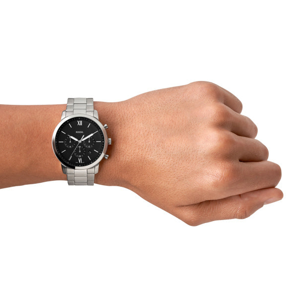 Hand wearing a silver Fossil Men's watch with a black face on a white background