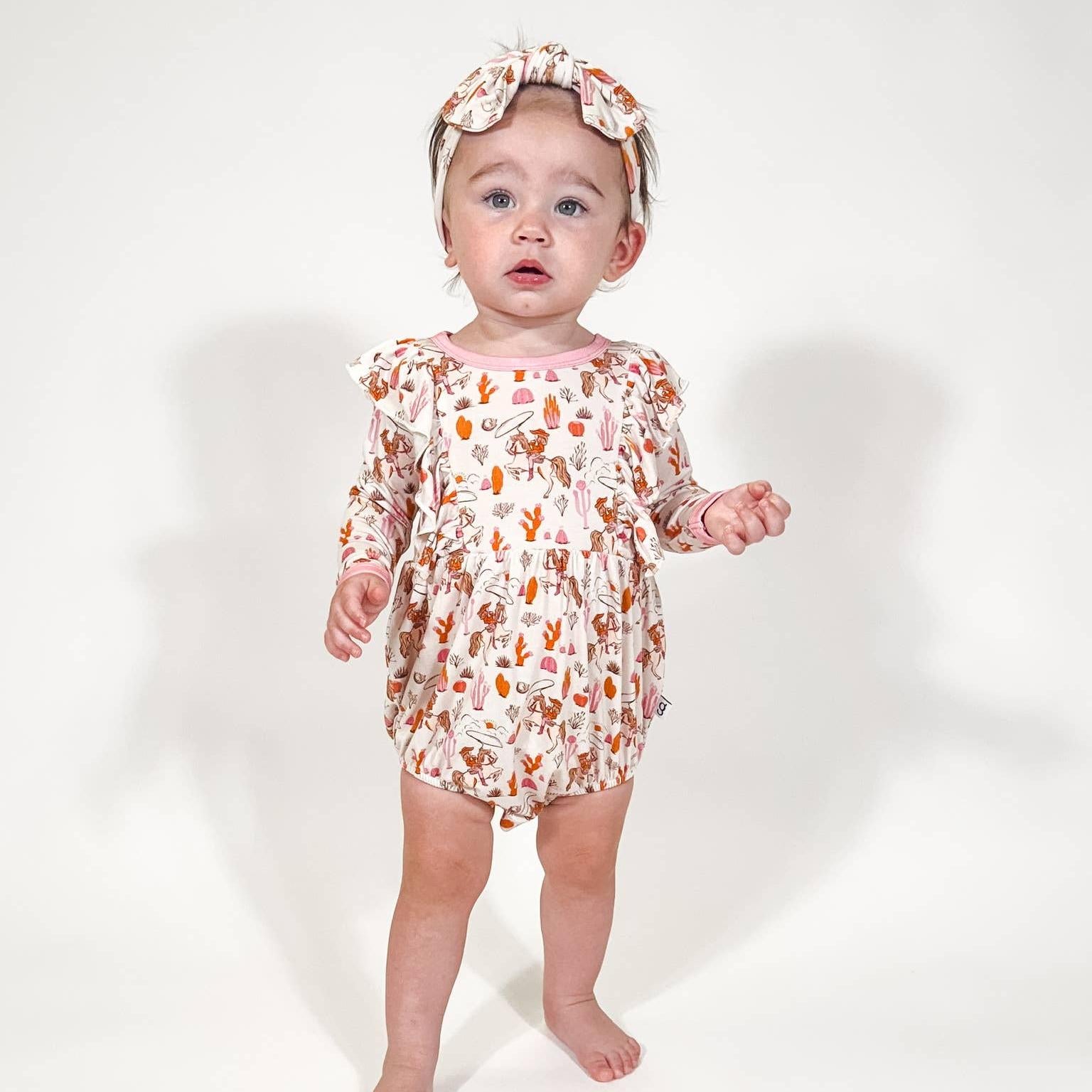 Baby wearing a floral dress and headband on a white background
