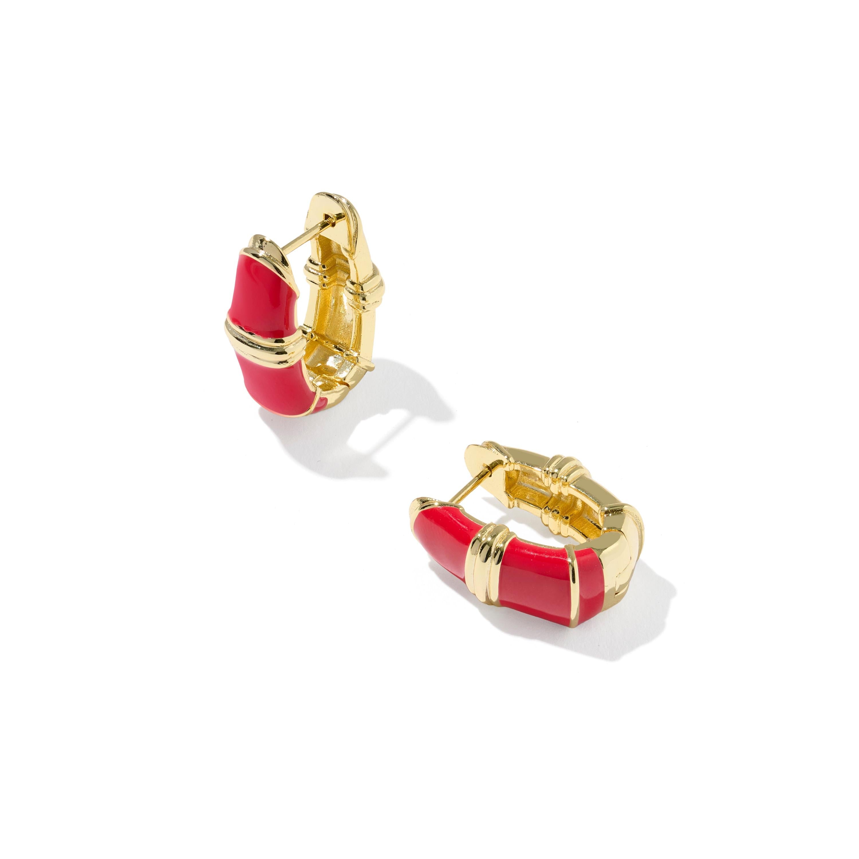 A pair of Kendra Scott gold huggie hoop earrings with curved red enamel inlays enamel inlays.