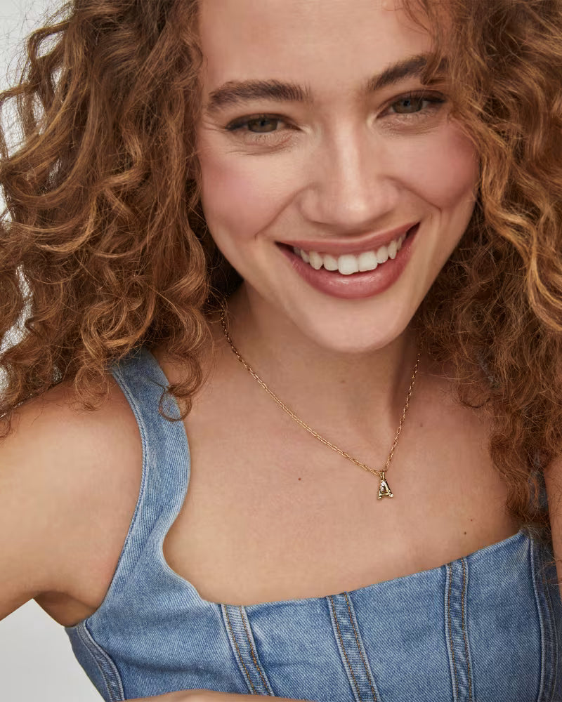 Woman wearing a Kendra Scott Crystal Letter Pendant Necklace against a neutral background