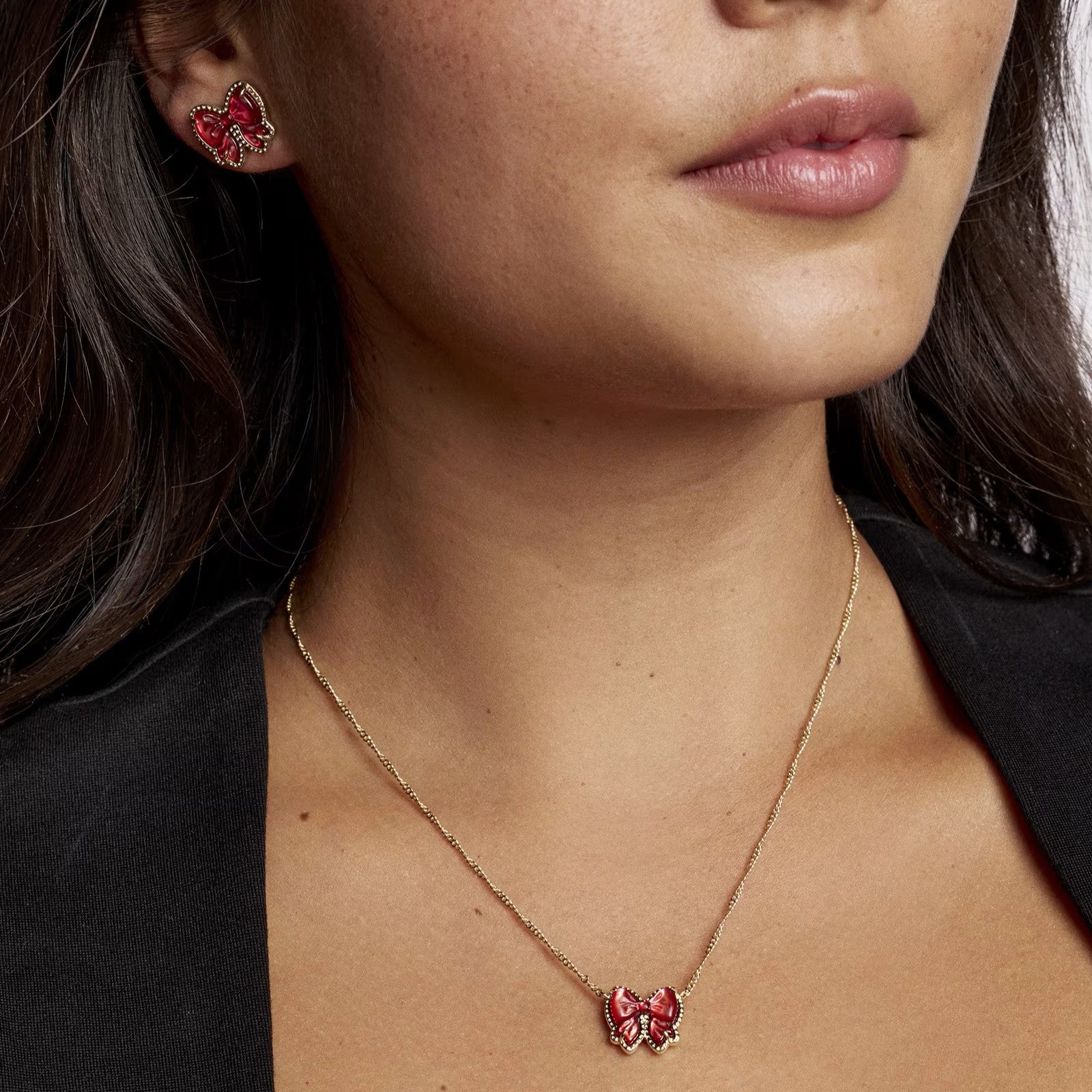 Close-up of a woman wearing the Kendra Scott Haley Bow earrings & necklace in red.