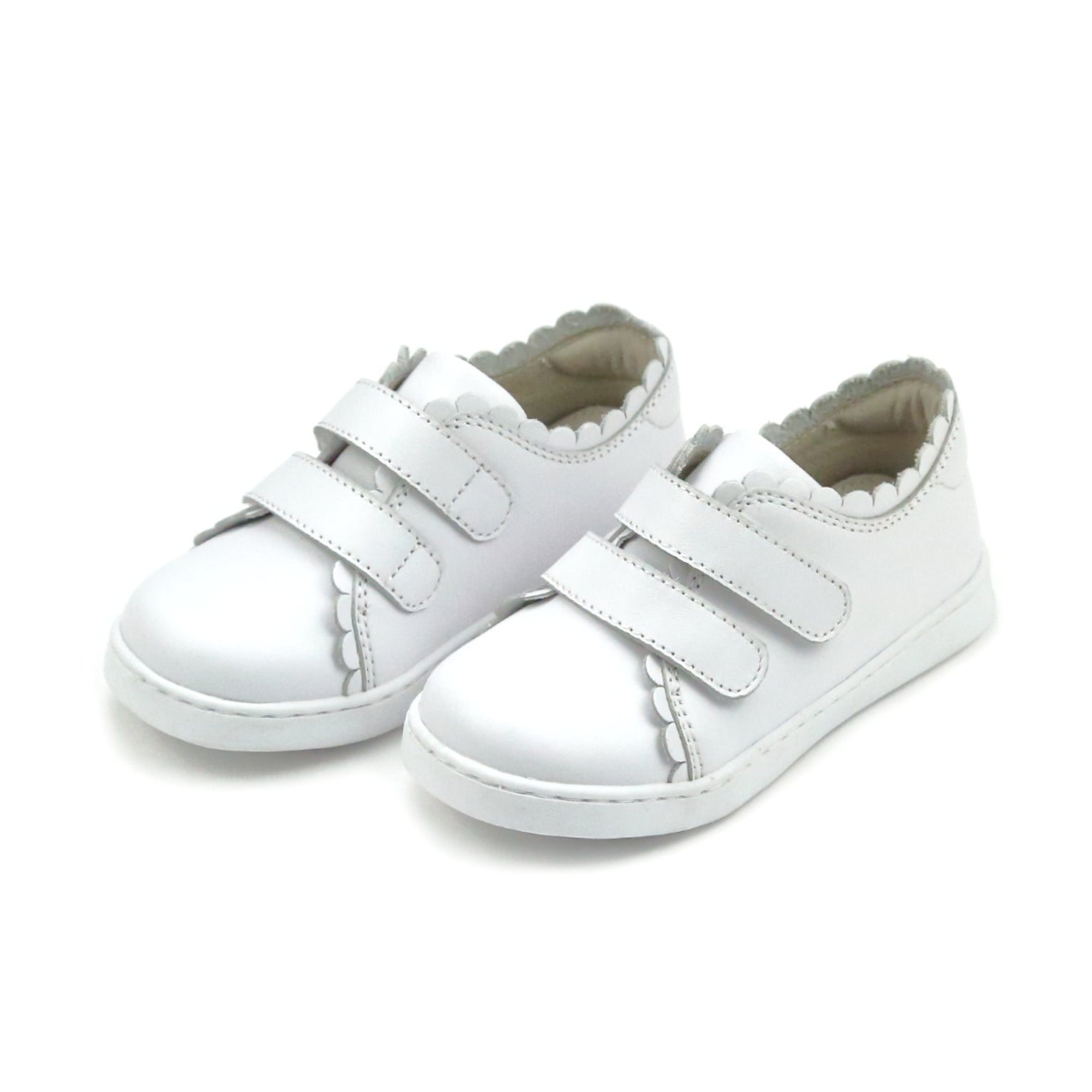 White children's sneakers with velcro straps on a white background