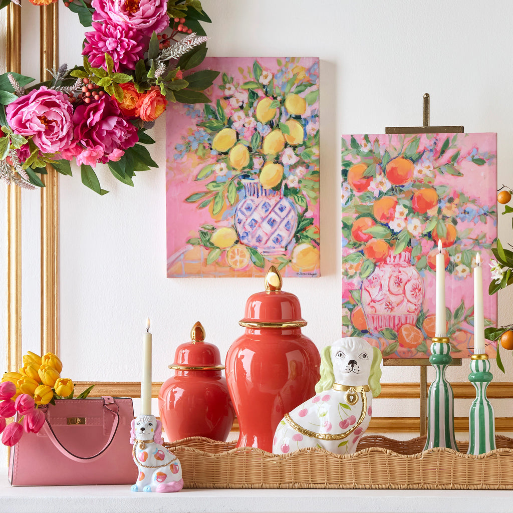 Decorative setting with floral arrangements, vases, and a pink handbag on a white surface.