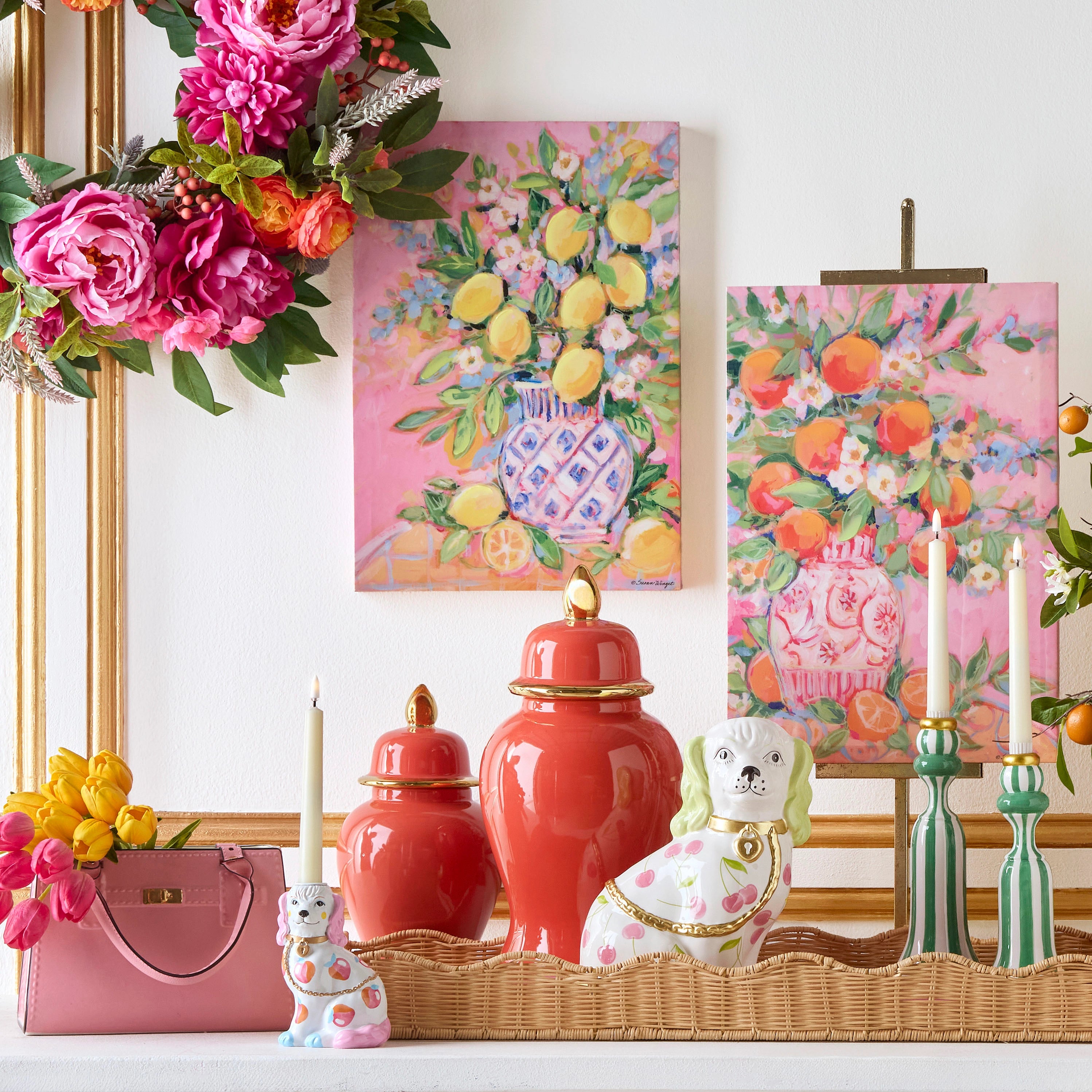 Decorative setting with floral arrangements, vases, and a pink handbag on a white surface.