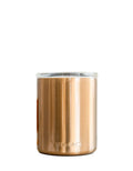 Rose gold tumbler with a blurred glass bottle in the background