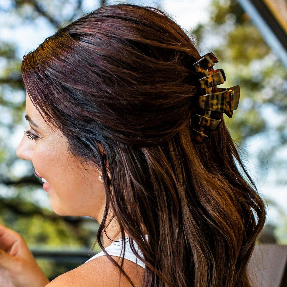 Woman with long brown hair wearing tortoiseshell hair clips outdoors