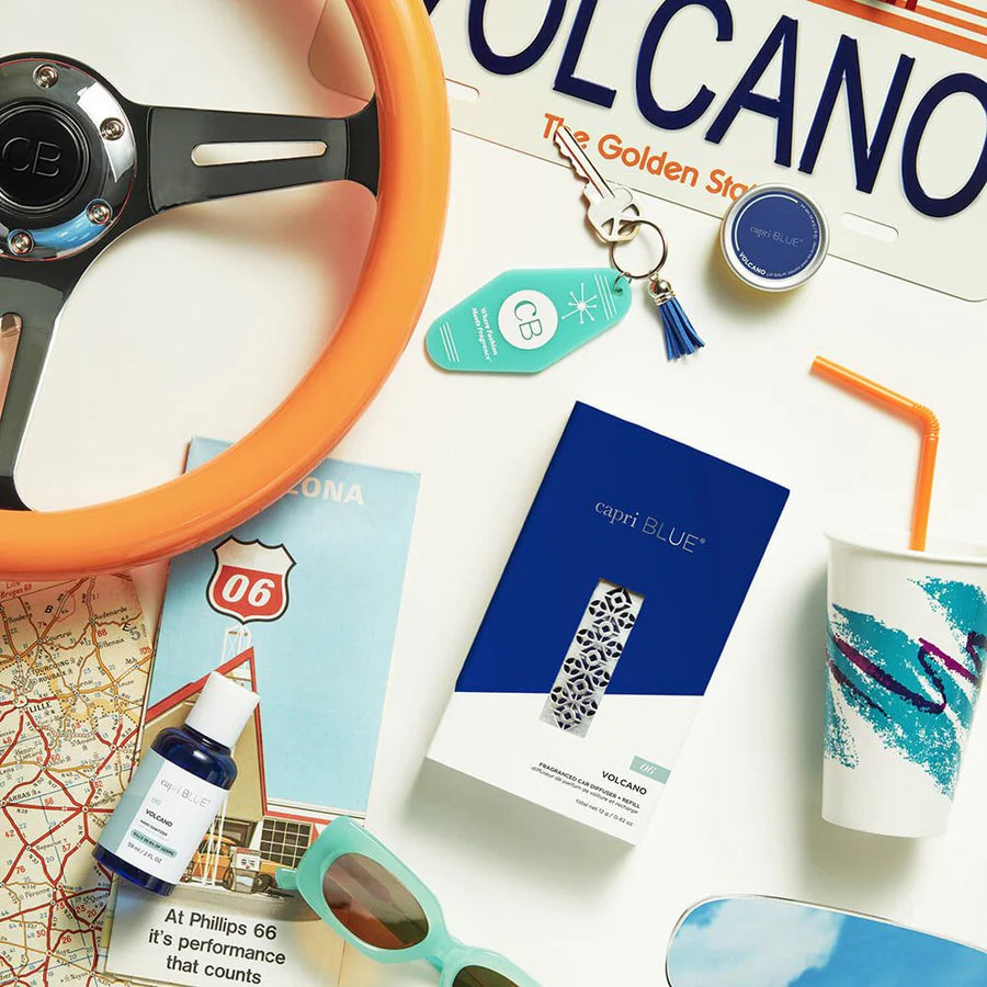 Collection of travel-themed items including a steering wheel, sunglasses, and a cup on a white surface.
