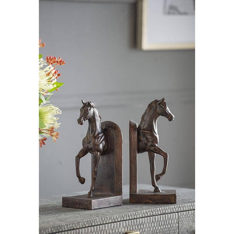 A pair of horse bookends with a dark bronze finish, displayed on a textured gray surface against a neutral gray wall background.