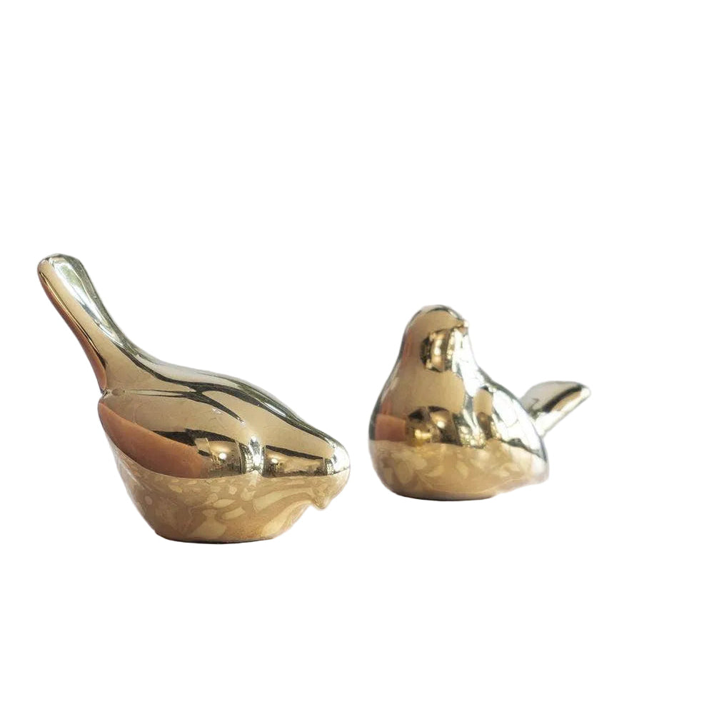 Two gold ceramic birds on a decorative surface with a light background