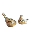 Two gold ceramic birds on a decorative surface with a light background
