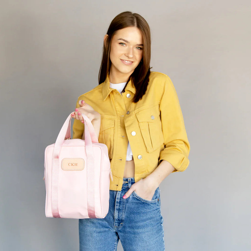 Woman holding a pink bag against a gray background