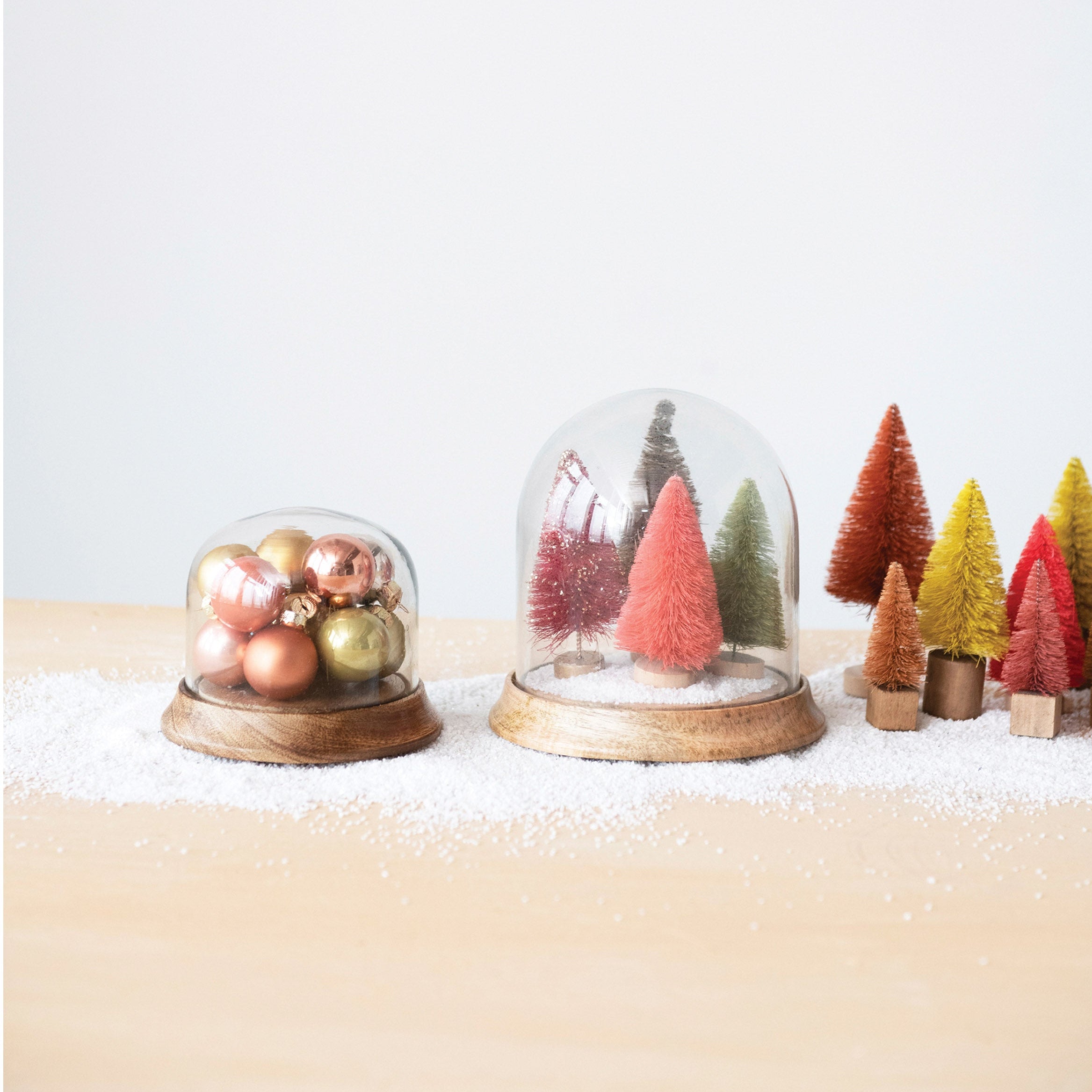 Decorative Christmas scene with glass domes and miniature trees on a white background